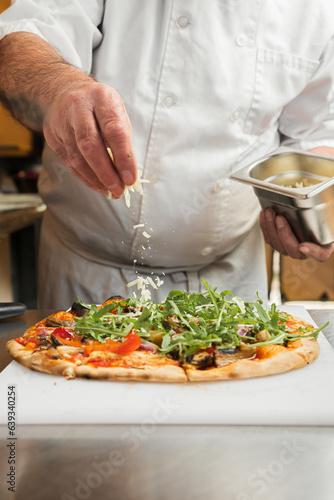 An Italian chef sprinkles freshly grated Parmesan cheese over a crispy pepperoni pizza, photo in motion