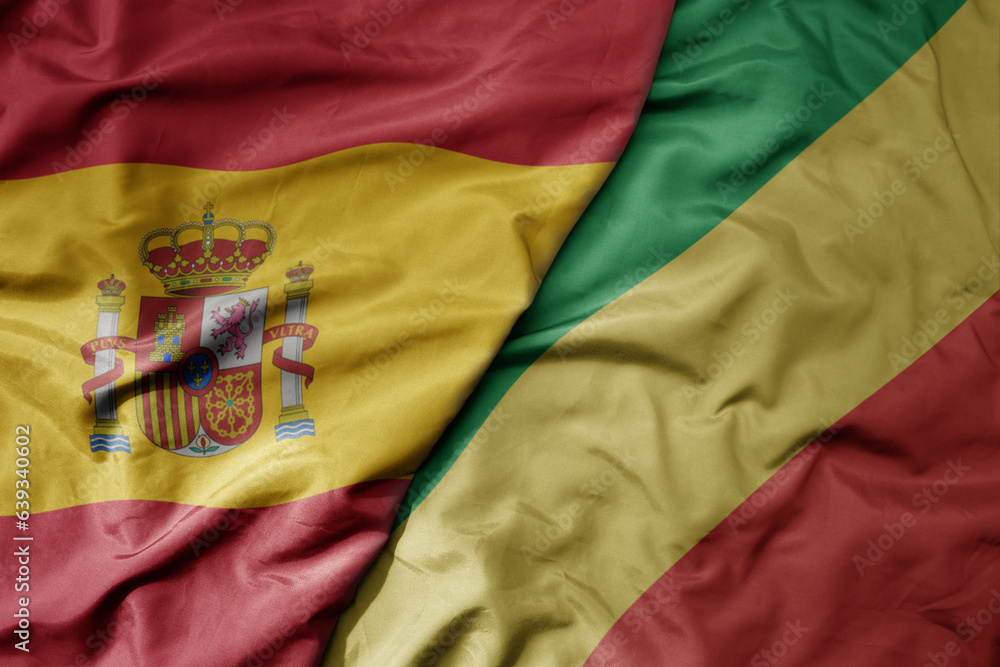 big waving national colorful flag of spain and national flag of republic of the congo . big waving national colorful flag of spain and national flag of republic of the congo .