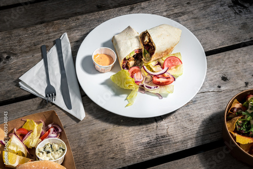 A quesadilla dish on a white plate at an outdoor café on a wooden table, clean cutlery and napkin