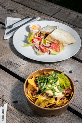 A quesadilla dish on a white plate at an outdoor café on a wooden table, clean cutlery and napkin
