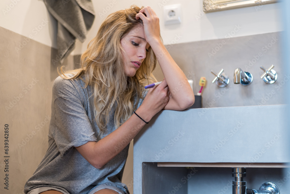 Worried sad woman Looking at a Pregnancy Test after results Worried sad woman Looking at a Pregnancy Test after results