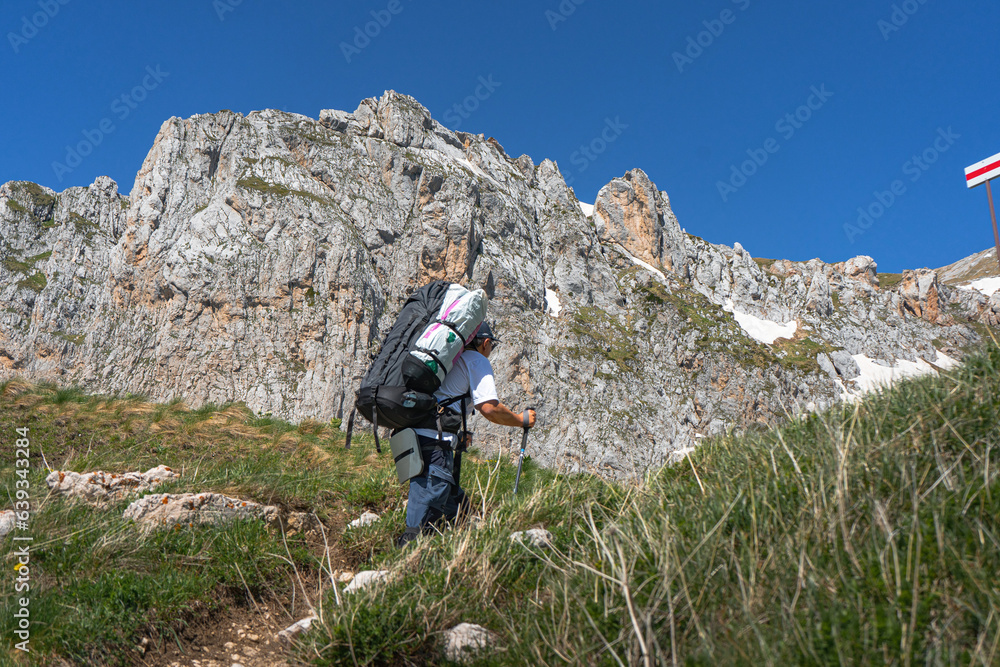 A tourist with a backpack walks along a path in the mountains.