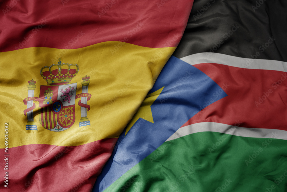 big waving national colorful flag of spain and national flag of south sudan . big waving national colorful flag of spain and national flag of south sudan .
