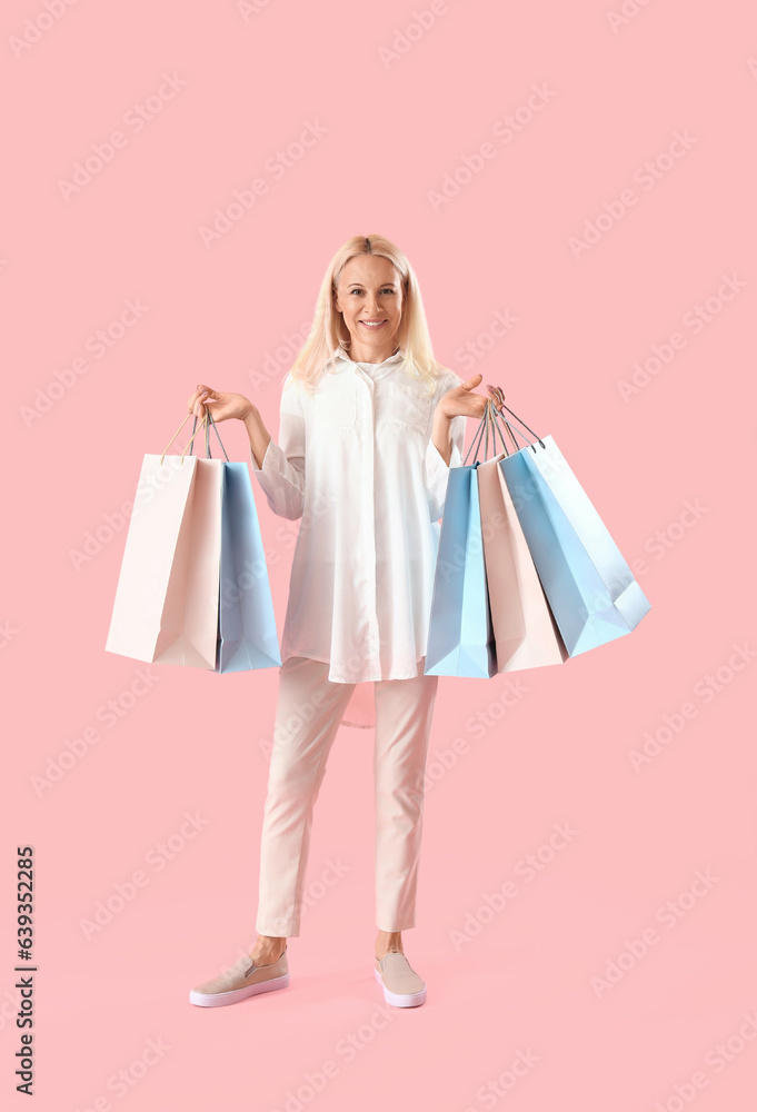 Mature woman with paper bags on pink background. Online shopping