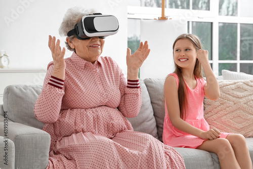 Little girl and her grandmother using VR glasses at home