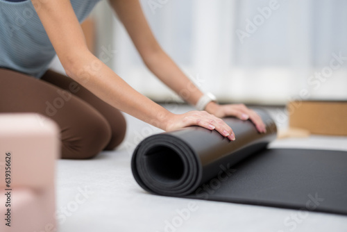 Woman hand roll up yoga mat at home