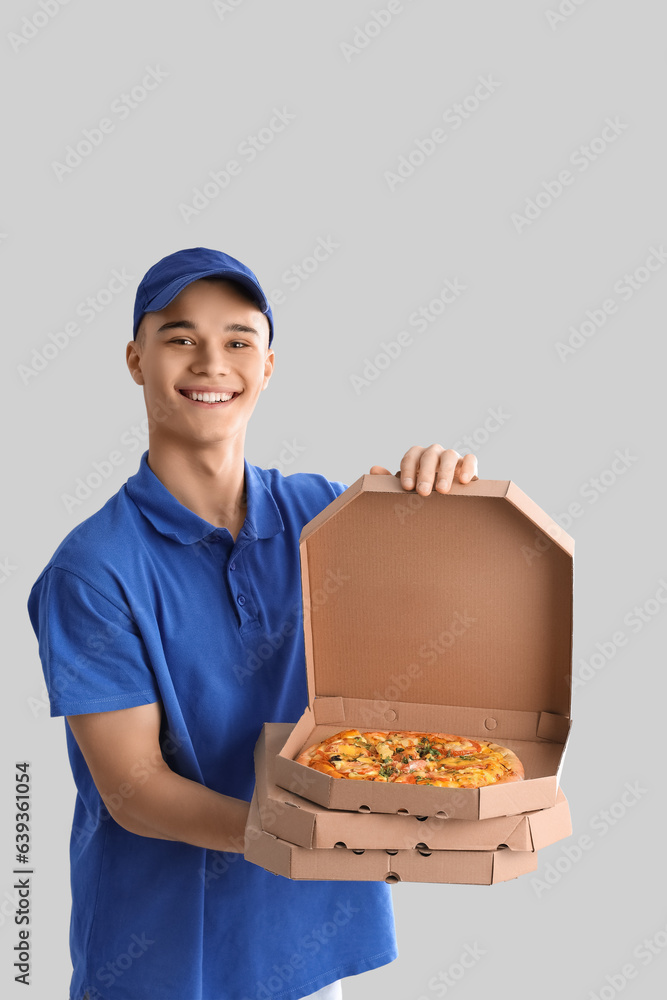 Young courier with pizza on light background Young courier with pizza on light background