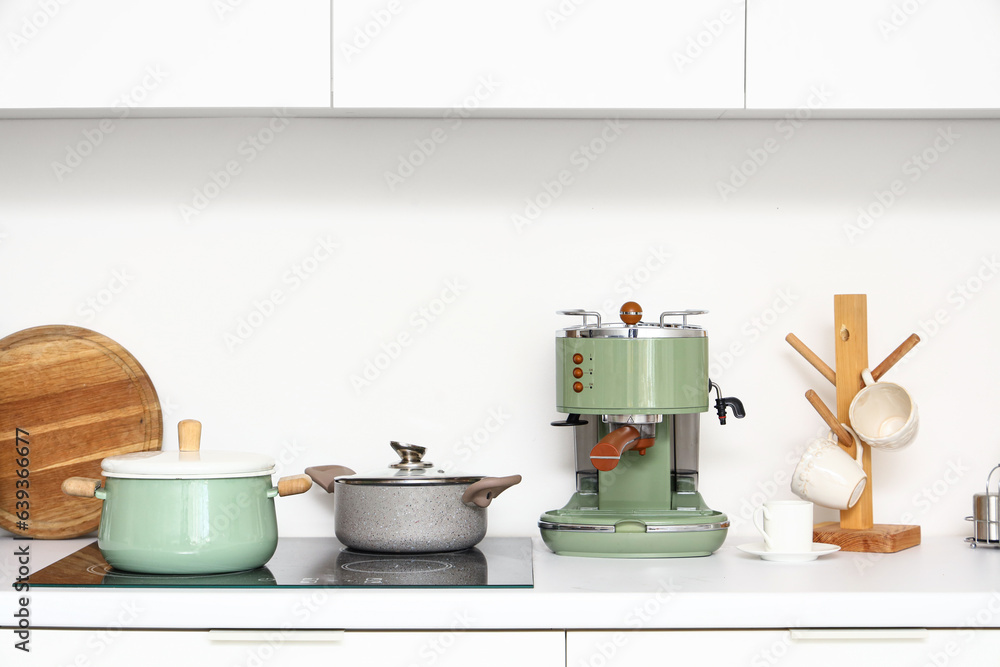 Coffee machine and cooking pots on white countertop in kitchen Coffee machine and cooking pots on white countertop in kitchen