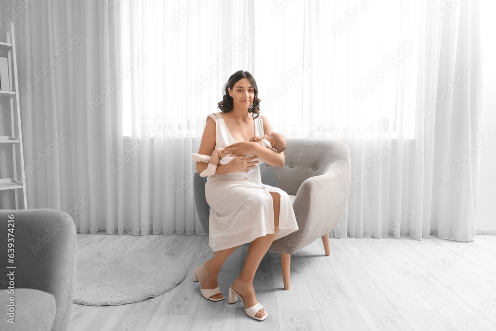 Young woman with her baby sitting in armchair at home Young woman with her baby sitting in armchair at home
