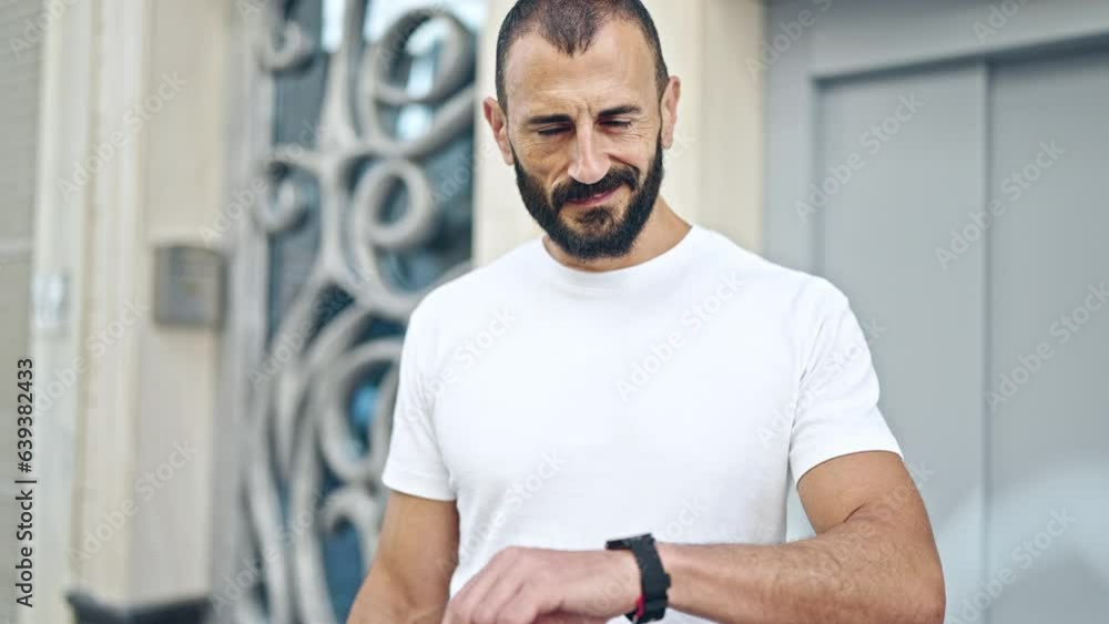 Young hispanic man smiling confident pointing to watch at street Young hispanic man smiling confident pointing to watch at street