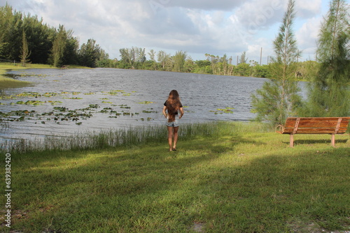 Fototapeta Naklejka Na Ścianę i Meble -  Long brunette hair on a young woman standing by the lake