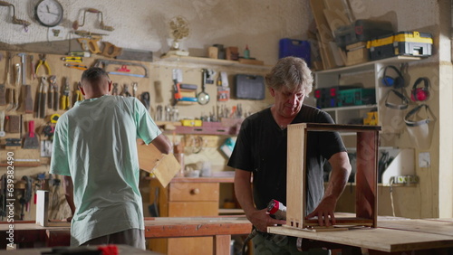 Carpentry shop scene of two carpenters working with tools to build and fix wood furniture