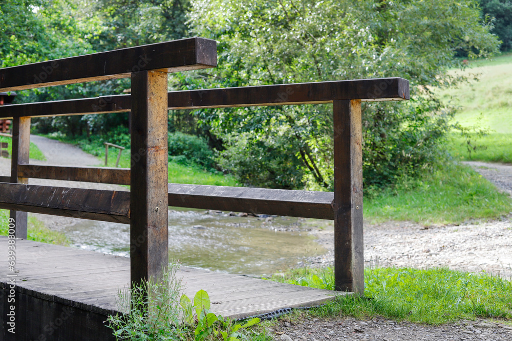 A wooden bridge across a shallow stream leading into a dark and stuffy forest. A wooden bridge across a shallow stream leading into a dark and stuffy forest.