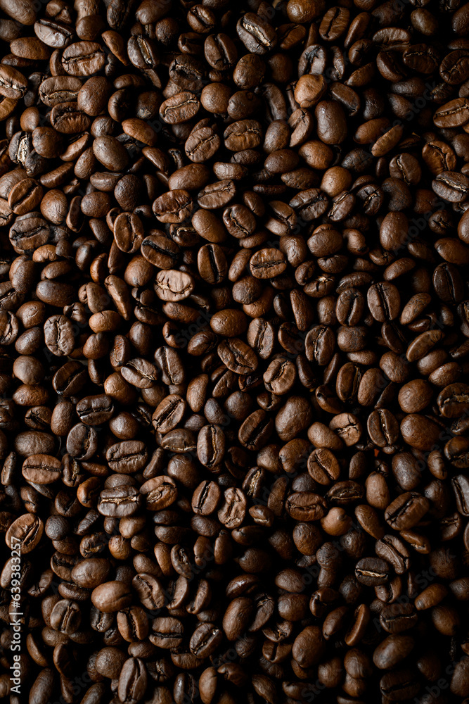 Naklejka premium Overhead view of dark brown fresh roasted coffee beans background. Copy space