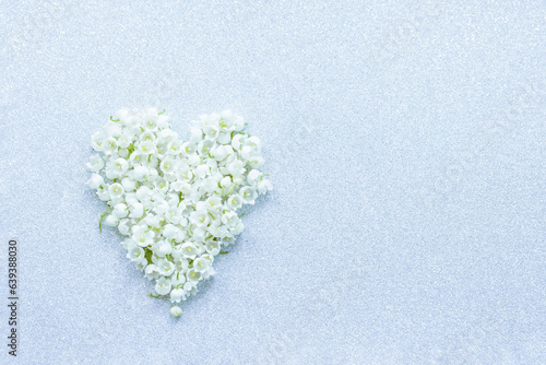 a heart made of lily-of-the-valley flowers. background with lily of the valley flowers top view. lilies of the valley in the form of a heart and a copy of the space.