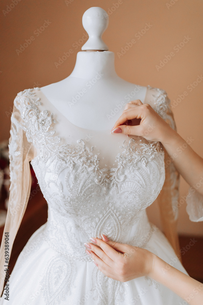 A happy bride is preparing for her luxurious wedding at home, holding her beautiful dress in her hands. Portrait of a woman with professional hair and makeup and a smile in a bathrobe A happy bride is preparing for her luxurious wedding at home, holding her beautiful dress in her hands. Portrait of a woman with professional hair and makeup and a smile in a bathrobe