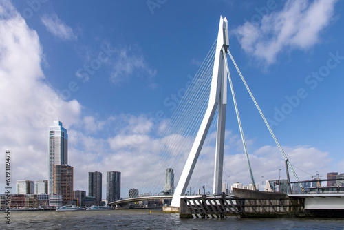 Rotterdam, the Netherlands-February 2023; Panoramic view over Maas river with Erasmus suspension bridge and downtown with skyscrapers Zalmhaven Tower and Cooltower against a white clouded blue sky