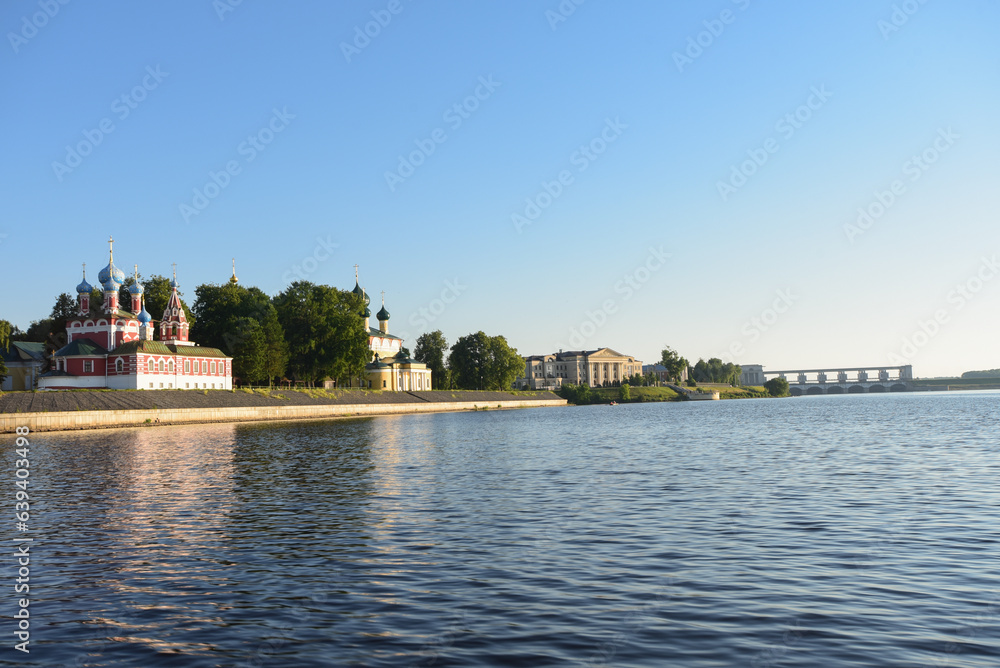view of the Uglich Kremlin from the Volga River, an ensemble of several preserved historical buildings, a sunny summer evening, cloudless blue sky