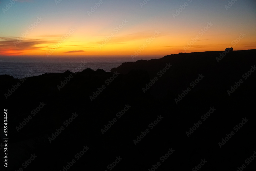 silhouette of camper vans parking on cliff during sunset  