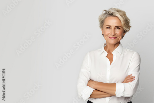 Mature business woman smiling confident with arms crossed looking like a corporate senior manager or an experienced female entrepreneur with positive energy standing against a white background.