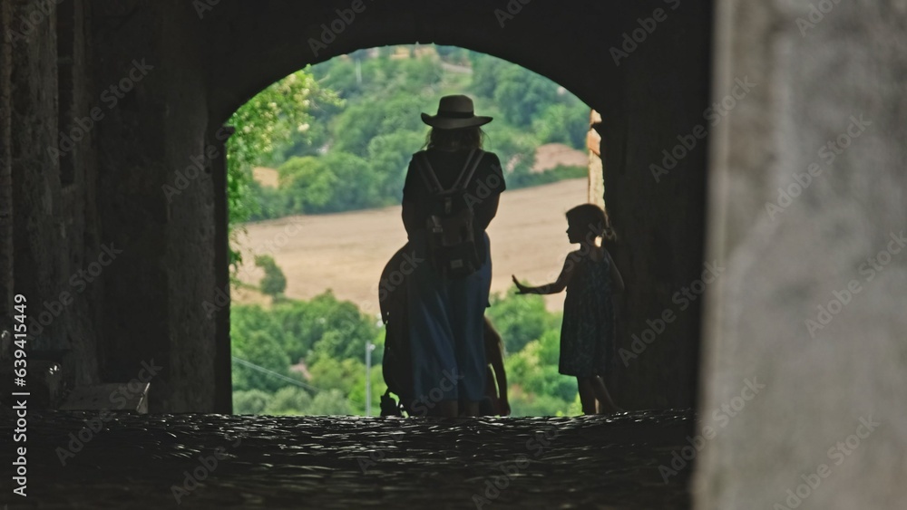 Silhouette of Female Tourist with Kids Walking Through City Gateway in Old Roman Italian City Silhouette of Female Tourist with Kids Walking Through City Gateway in Old Roman Italian City