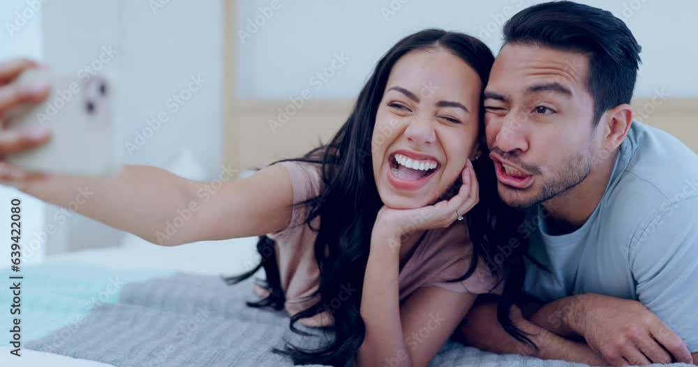 Couple in bedroom, selfie and smile for social media, memory and live streaming with funny face at home. People relax in bed together, fun and healthy relationship, happy in picture in the morning Couple in bedroom, selfie and smile for social media, memory and live streaming with funny face at home. People relax in bed together, fun and healthy relationship, happy in picture in the morning
