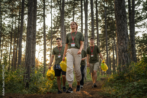 teenage friends young men women pick up waste garbage to clean forest