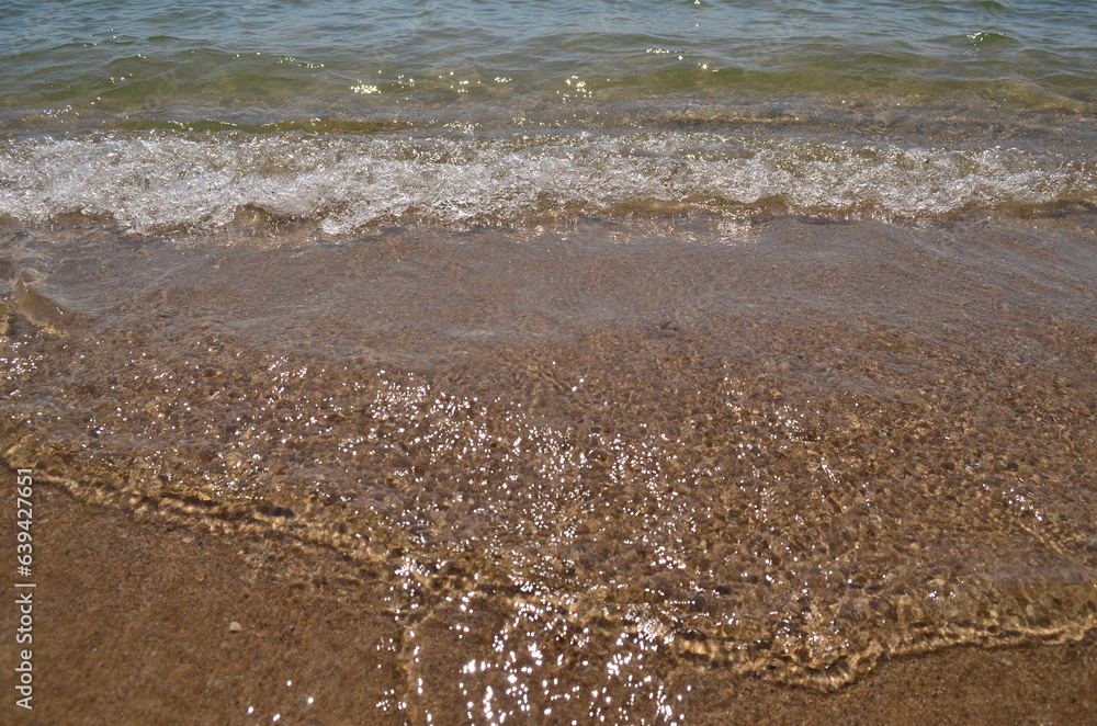 Sea water splashes on the shore under the sun Sea water splashes on the shore under the sun