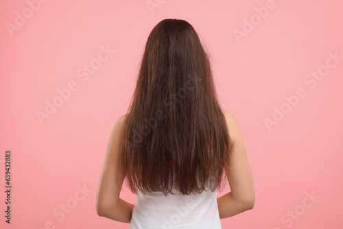 Woman with damaged hair before treatment on pink background, back view