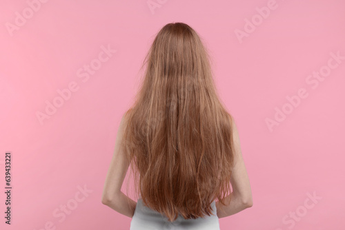 Woman with damaged hair on pink background, back view