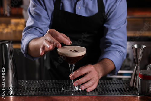 Bartender preparing Espresso Martini in bar, closeup. Alcohol cocktail