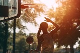 Ground level back view of anonymous female basketball player throwing ball in hoop on sports ground on sunny day