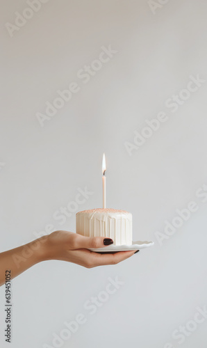Hand holding birthday cake with lit candles, minimalistic  food photography