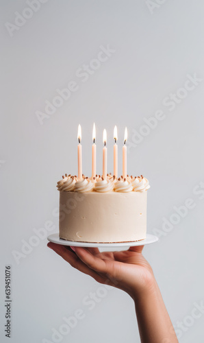 Hand holding birthday cake with lit candles, minimalistic  food photography © piknine