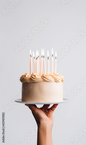 Hand holding birthday cake with lit candles, minimalistic  food photography