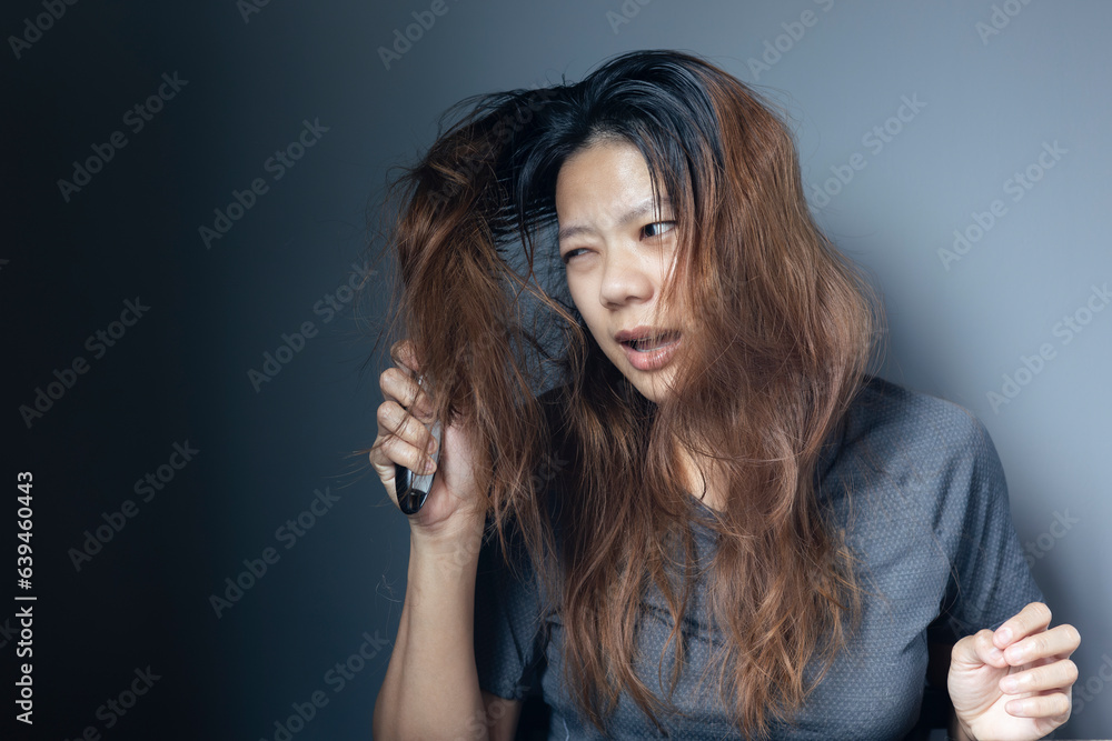 Asian girl with a comb and problem hair on gray background. Asian young woman holding brush, hairbrush with long loss hair problem after brushing. Asian girl with a comb and problem hair on gray background. Asian young woman holding brush, hairbrush with long loss hair problem after brushing.