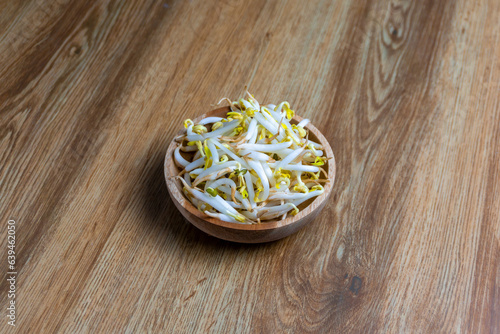 Beansprout in wooden bowl. Mungbean sprouts on wooden background. photo