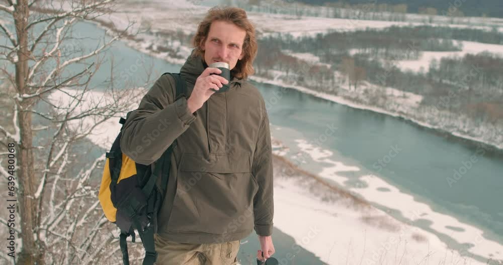 relaxed calm young backpacker enjoying beauty of landscape, nature, drinking coffee on top of rock, mountain Slow motion Enjoyment Frozen river in background Tea at frosty day Winter holidays, tourism relaxed calm young backpacker enjoying beauty of landscape, nature, drinking coffee on top of rock, mountain Slow motion Enjoyment Frozen river in background Tea at frosty day Winter holidays, tourism