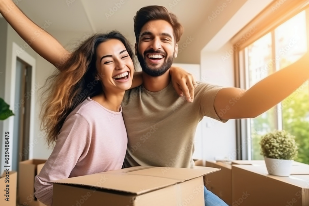 Young happy married couple in their new home after moving in. Unpacking boxes after moving into a new apartment. New homeowners. Mortgage. Rental of property. Young happy married couple in their new home after moving in. Unpacking boxes after moving into a new apartment. New homeowners. Mortgage. Rental of property.
