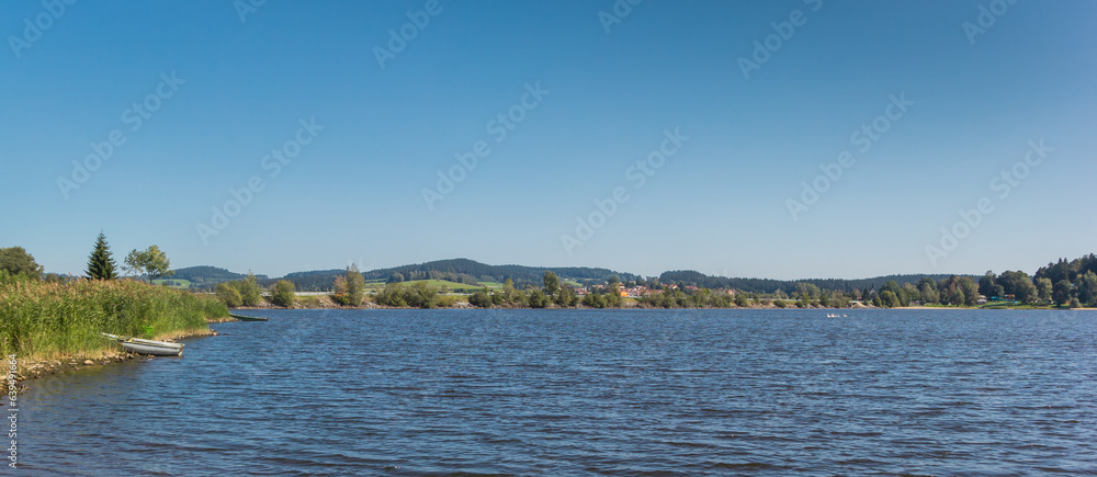 Obraz premium Panorama of a little rowing boat at the shore of lake Lipno in the Sumava mountains, Czech Republic