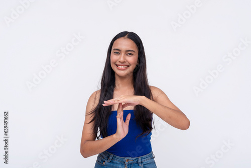 A friendly young Filipino woman requests for a time out or break. Gesturing with her hands. Isolated on a white background. photo
