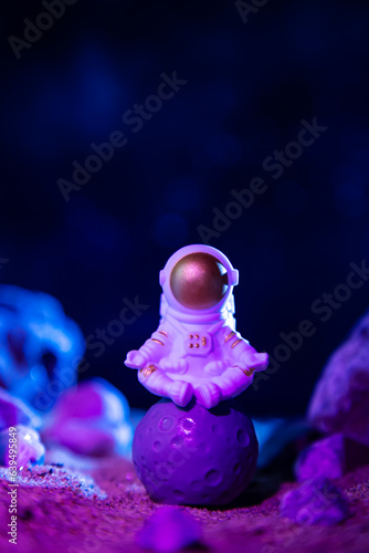 Astronaut in a spacesuit sits on the rocky surface of the planet.