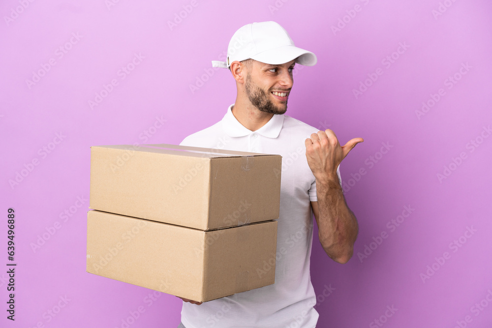 Delivery caucasian man isolated on purple background pointing to the side to present a product Delivery caucasian man isolated on purple background pointing to the side to present a product