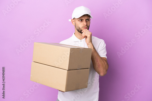 Delivery caucasian man isolated on purple background having doubts and thinking © luismolinero