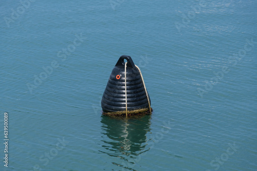 Eine schwarze, geriffelte Boje auf dem Meer bei ruhiger See (nautic sea buoy - calm sea)