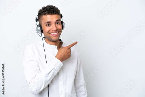 Telemarketer Brazilian man working with a headset isolated on white background pointing finger to the side