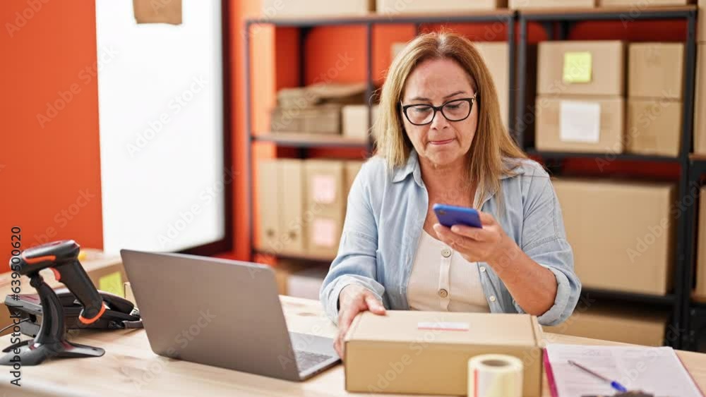 Middle age hispanic woman ecommerce business worker make photo to packages at office Middle age hispanic woman ecommerce business worker make photo to packages at office