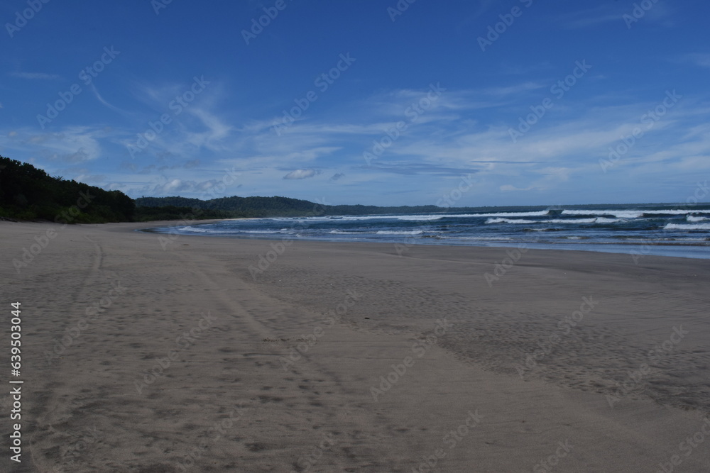 View of a wide beach in Indonesia with a clear blue sky and no people on it. 