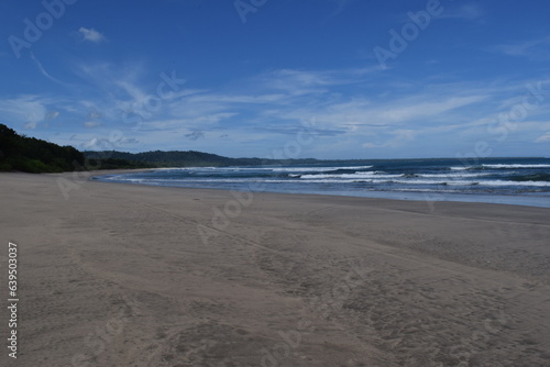 View of a wide beach in Indonesia with a clear blue sky and no people on it. 