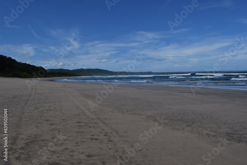 View of a wide beach in Indonesia with a clear blue sky and no people on it. 